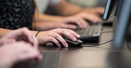 Someone typing and useing a mouse on a computer