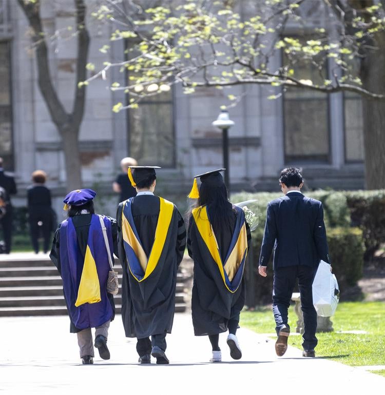 University graduates walk through the Cathedral of Learning lawn 